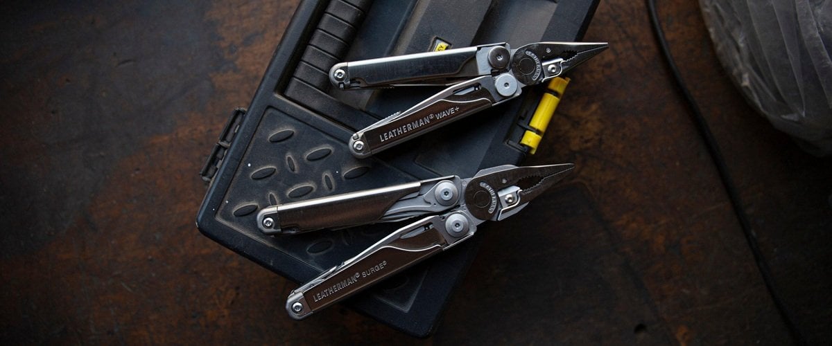 Açık vaziyette duran bir multitool (çok amaçlı çakı) ve yanında küçük parçalar, ahşap bir zemin üzerinde